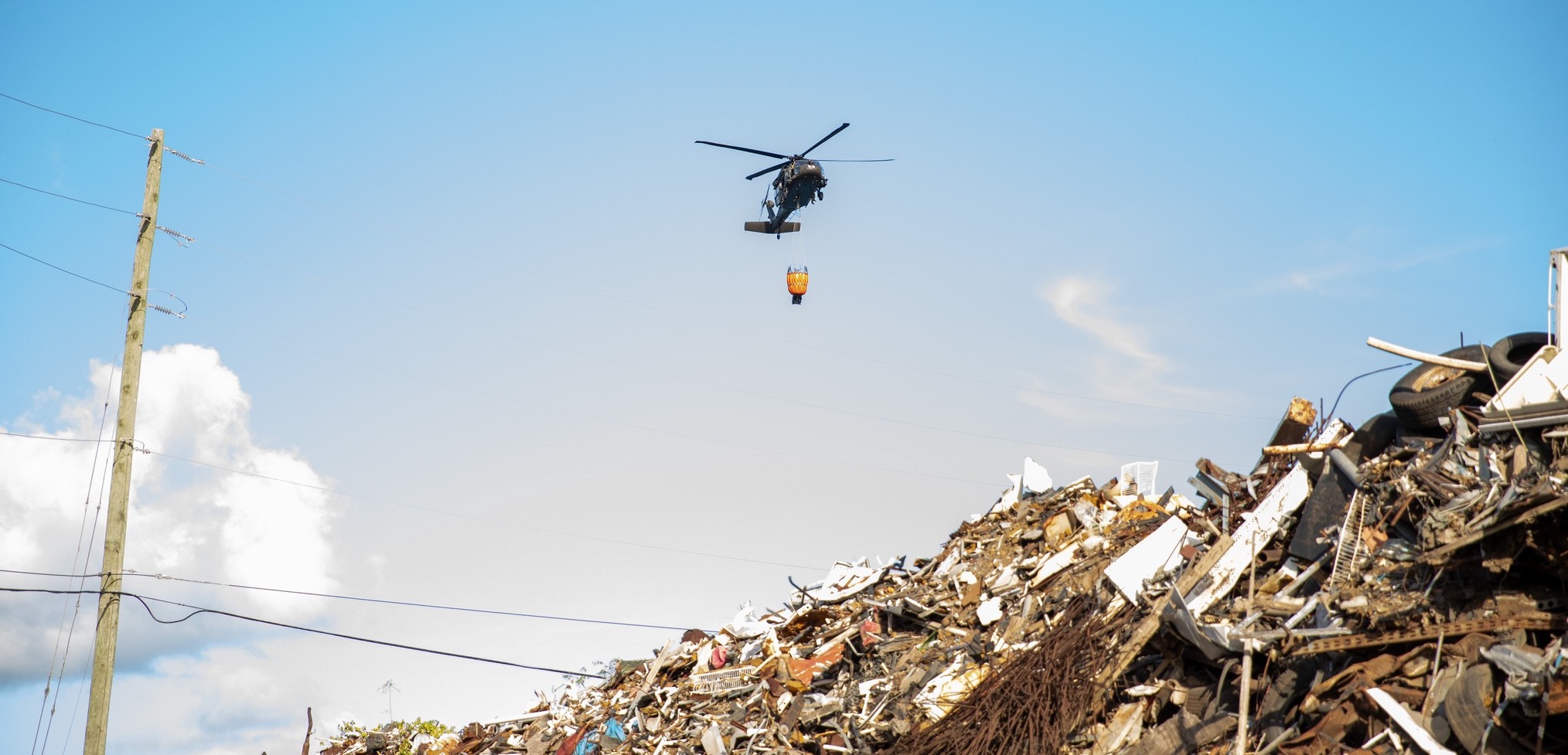 A Puerto Rico National Guard Blackhawk helicopter outfitted with a "Bambi bucket" prepares to dump water on the Bovoni landfill fire on St. Thomas. (Photo courtesy Government House)