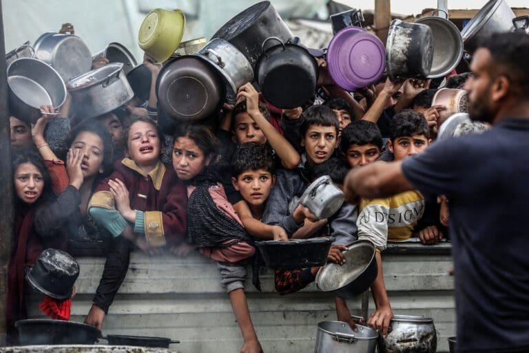 Displaced Palestinians in Al-Mawasi crowd to get rice meals due to the lack of flour and also the lack of entry of aid, in the southern Gaza Strip, on Nov. 29. (Shutterstock photo by Anas-Mohammed)