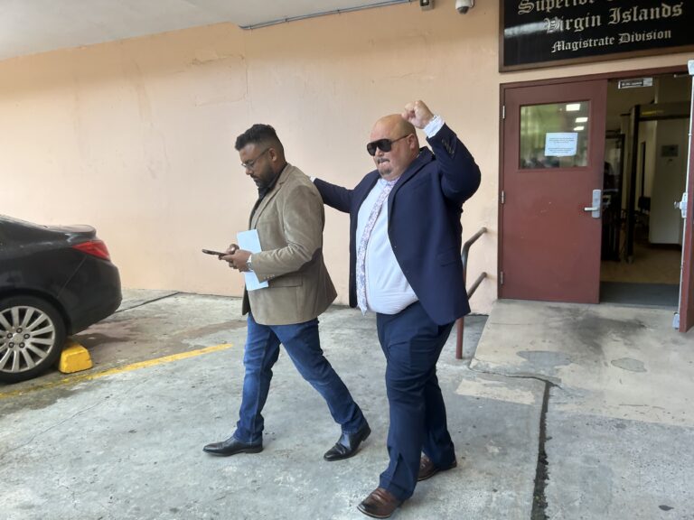 Brett "Mac" McClafferty raises his fist in the air as he leaves Magistrate Court Friday on St. Thomas with his business partner, Sunil Sharma. (Source photo by Siân Cobb)